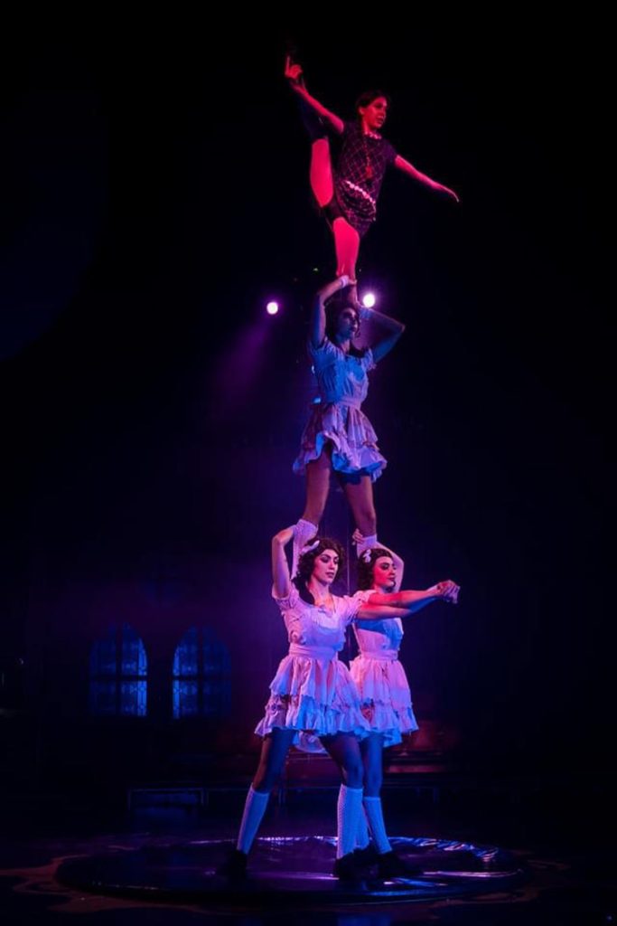 Dos intérpretes realizan una figura acrobática en pareja bajo luz azul.